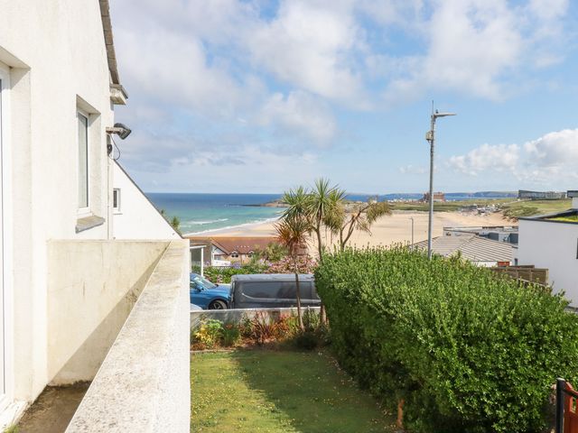An outdoor view of a beach and ocean with houses at 22 Pentire Avenue in Newquay