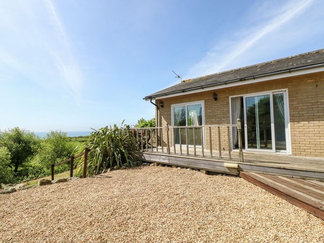 A gravel yard with wooden deck and railing outside a brick house near Ventnor