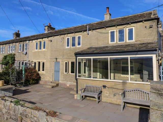 An outdoor view of a house with benches and windows at 1 Flush House Lane, Holmbridge