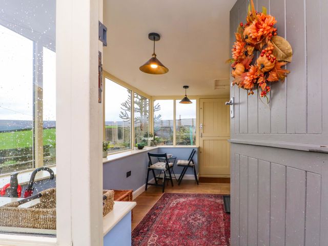 A conservatory with a table and chairs at Stone & Fleece Cottage in Holmbridge