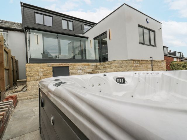 A hot tub with a view of a modern house at Ellis House in Huddersfield