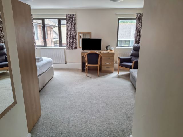 A bedroom with a bed, chair, TV, desk at The Driftwood Dwelling at Marine Court Littlehampton
