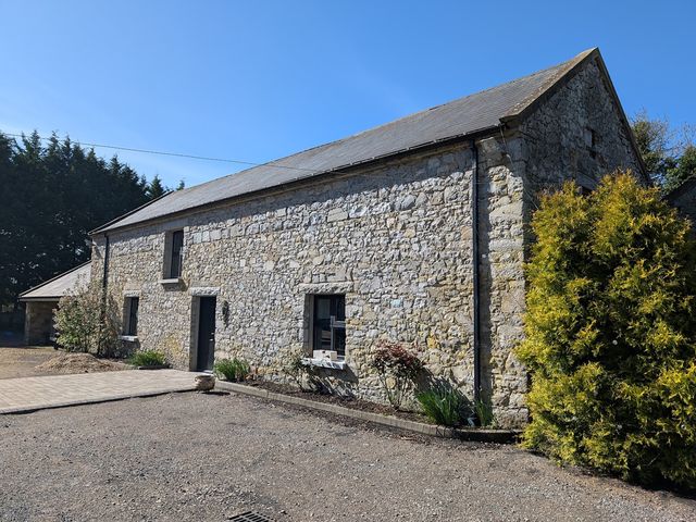 A stone house with windows and a driveway at Dunville Lodge in Rhode