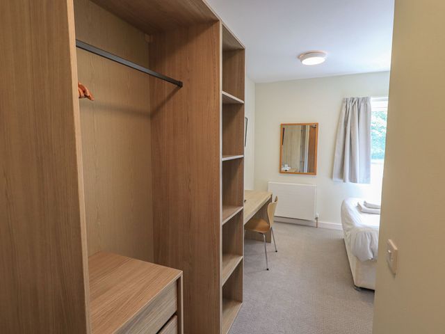 A bedroom with a wardrobe and a table at Eamont Park First-floor Double Bedroom in Penrith