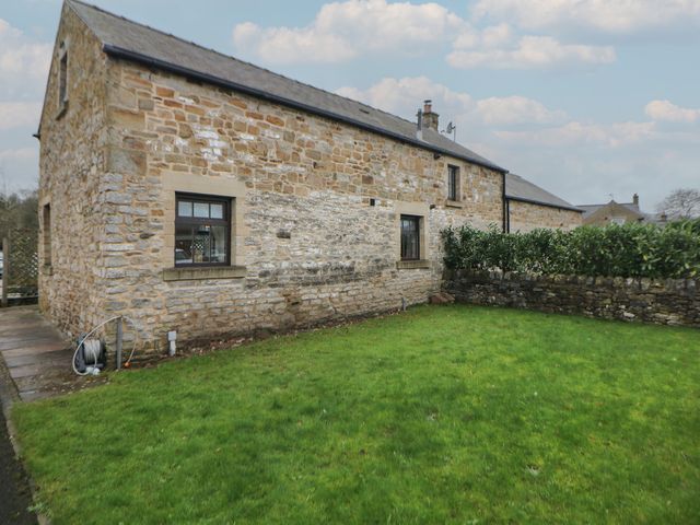 An outdoor view of a stone building with garden at Win Hill View Cottage in Hope Valley