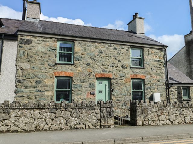 A stone house with windows and fence at Rhows in Niwbwrch (Newborough)