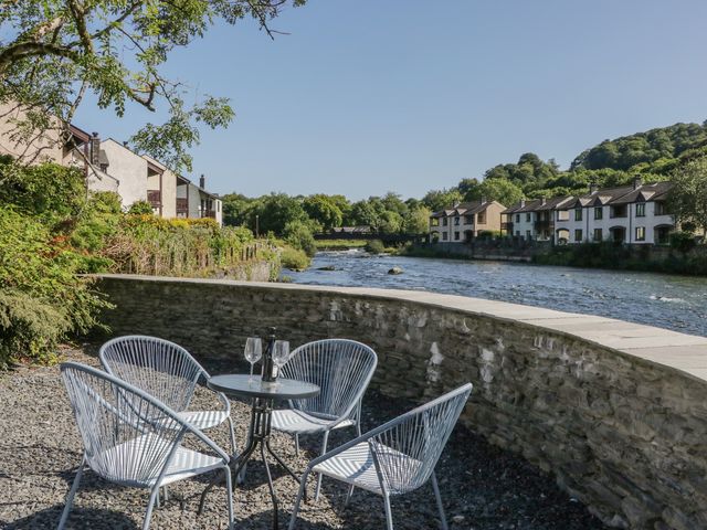 An outdoor seating area by a river at Old Post Office Cottage in Backbarrow near Newby Bridge