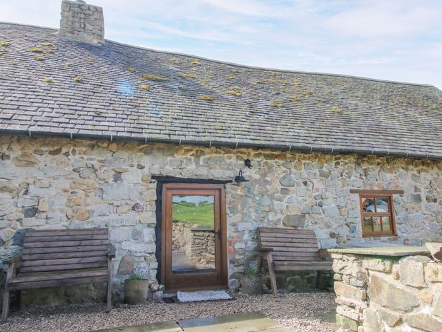An outdoor area with a stone wall and benches at The Long House near Trefonen