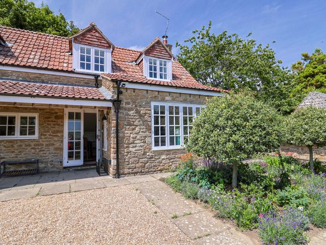 A house with windows and a garden at Tithe Barn Cottage in Litton Cheney near Burton Bradstock