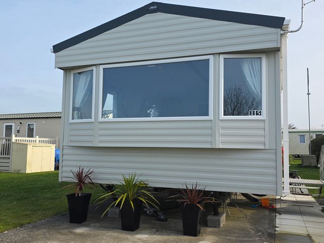 A mobile home with planters outside at Pines 15 Porthcawl