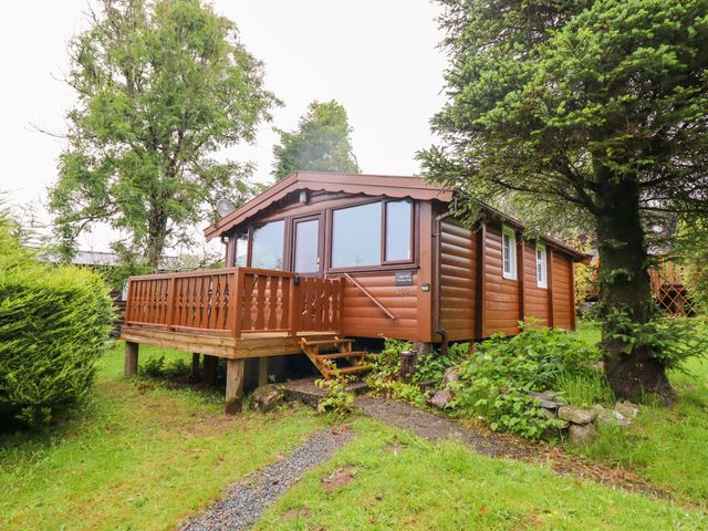A cabin with a deck and steps surrounded by trees at Y Bwthyn Pren, Cabin 209, Trawsfynydd