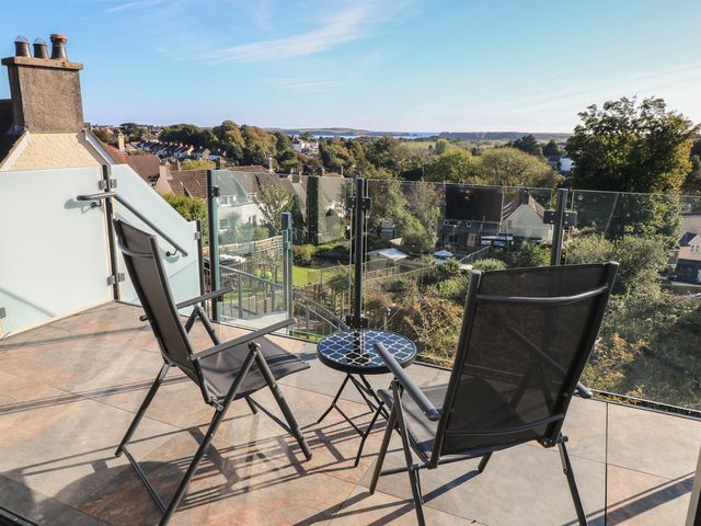 A balcony with chairs and a table overlooking a view at 10 Brython Place Tenby