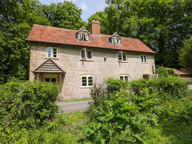 A house with a porch surrounded by greenery at Keepers Cottage in Devizes