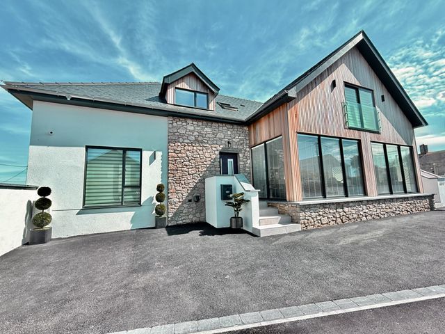 A house with stone wall and large windows at Ardwyn Rhosneigr