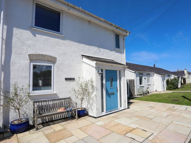 An outdoor view of a house with a blue door and bench at 15 Llwyn Gwalch Estate Pwllheli