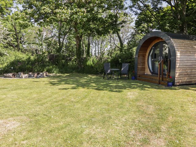 A grassy yard with a wooden pod and two chairs with a small table at Florence Pod in Pembroke