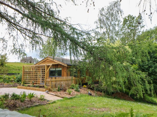 A wooden cabin with a garden and gravel path at Stoney Rock Lodge