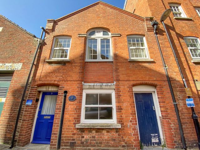 A red brick building with blue doors and white framed windows at Old Malthouse Apartment in Weymouth