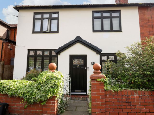 A front view of a house with a black door and windows at St Mary's House in Oldham