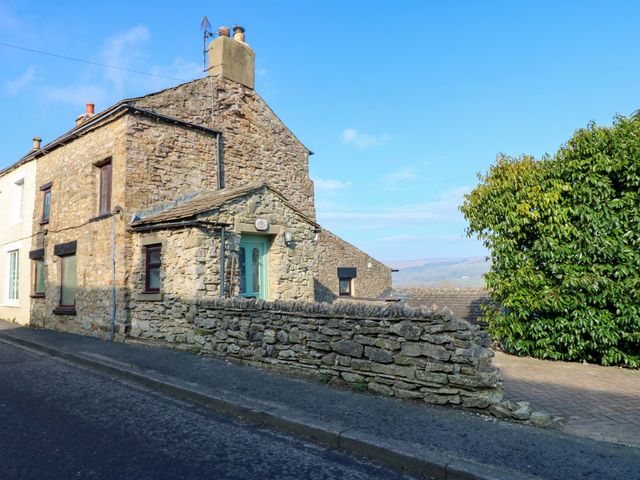 A stone house with windows and a door in a residential area at Eastend Cottage