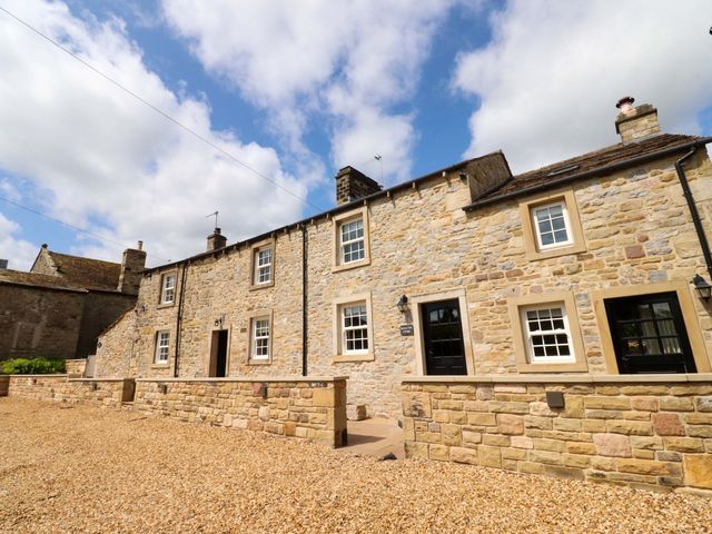 A stone house with gravel pathway at Rose Tree Cottage in Skipton