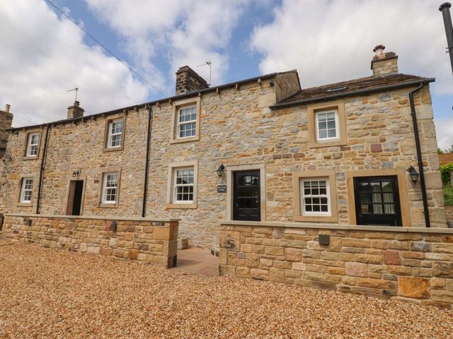 An outdoor view of a stone cottage with windows and a door at Rowan Tree Cottage Skipsea
