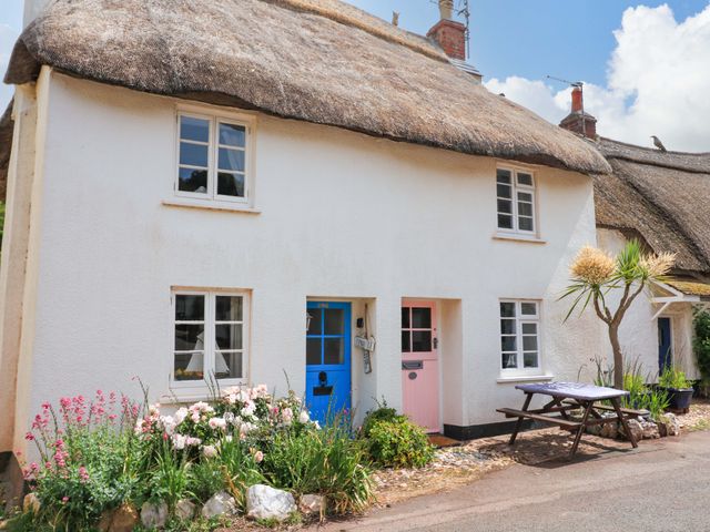 A cottage with a thatched roof and colorful doors at 2 The Square Hope Cove