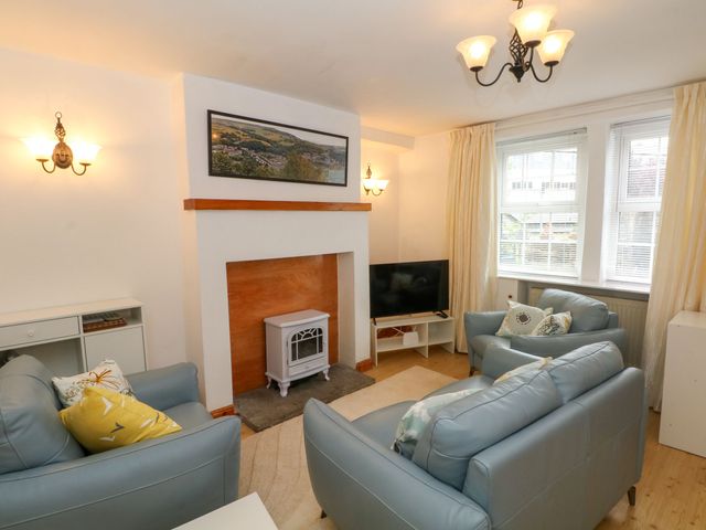A living room with a sofa, television, and a fireplace at Holme Cottage in Hebden Bridge