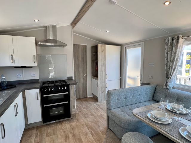 A kitchen with a stove and dining area at Mariner's Meadow - Hayling Island
