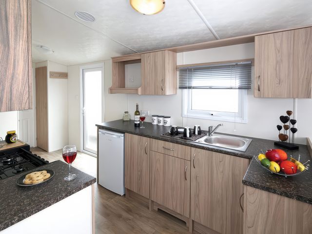 A kitchen with a sink, stove, refrigerator, and fruit bowl at Mariner's Meadow - Hayling Island