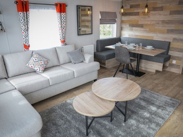 A living room with a sofa and dining area at Sandy Shores - Hayling Island