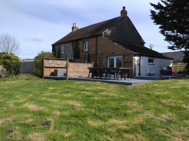 A house with a deck and seating area at Sunset Cottage in Gorran Churchtown