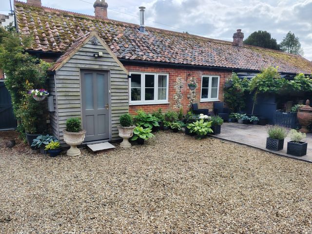 A garden with plants and a wooden garden shed at Cosy Cottage in North Elmham