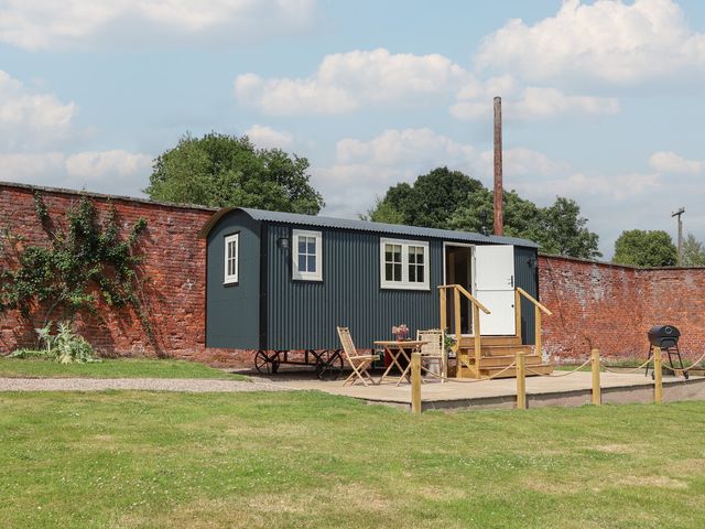 A shepherd's hut with outdoor seating area at Shepherd's Hut in Wrexham