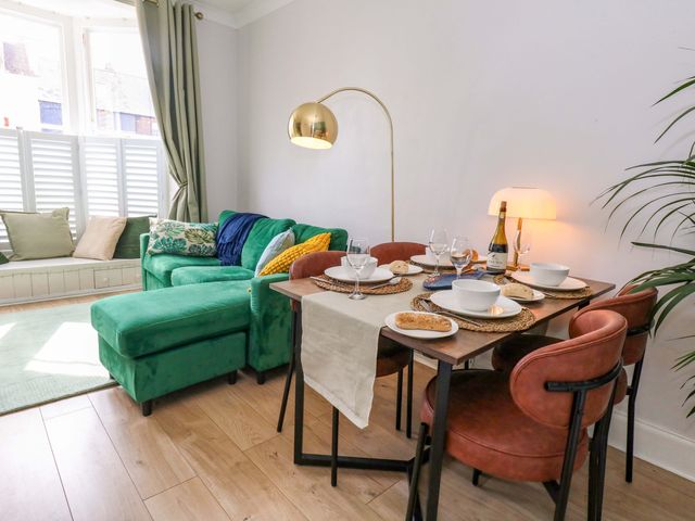 A living room with a dining table and sofa at Seagull & Chips in Weymouth