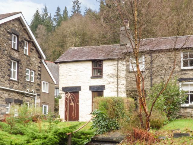 A house with a door and windows in the garden at Squirrel Cottage in Betws-Y-Coed