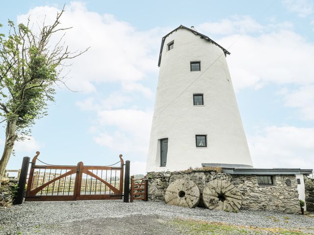 An outdoor view of a windmill with wooden gates at The Old Cornmill in Cemaes Bay