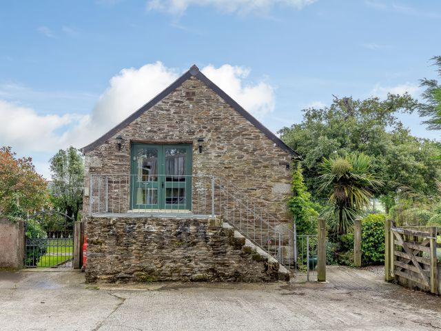 A stone building with a green door at the top of stairs surrounded by plants at The Loft in Bodrean near Truro
