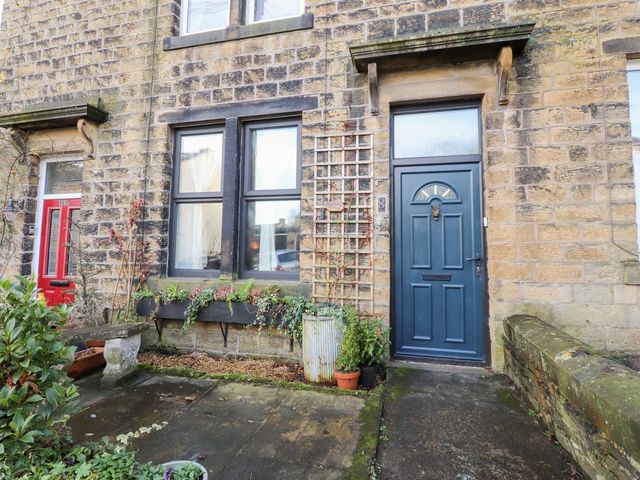 A front entrance with a blue door and plants at Heathcliff Cottage