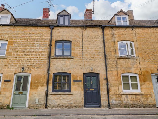 A row of stone houses with front doors and windows at Elm Cottage Moreton-In-Marsh