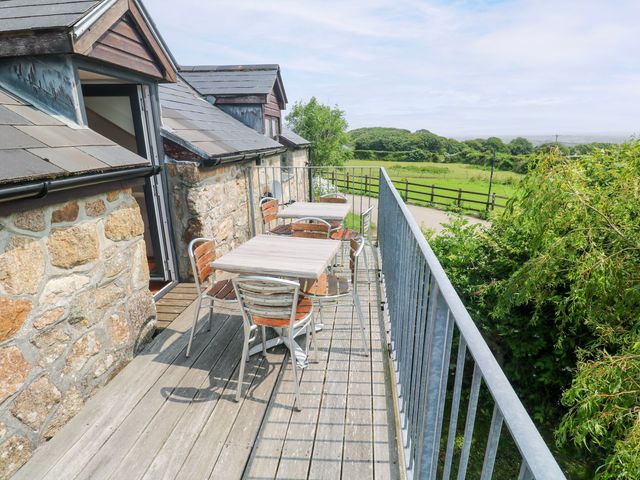A patio with tables and chairs overlooking a grassy area at The Cottage in St. Ives