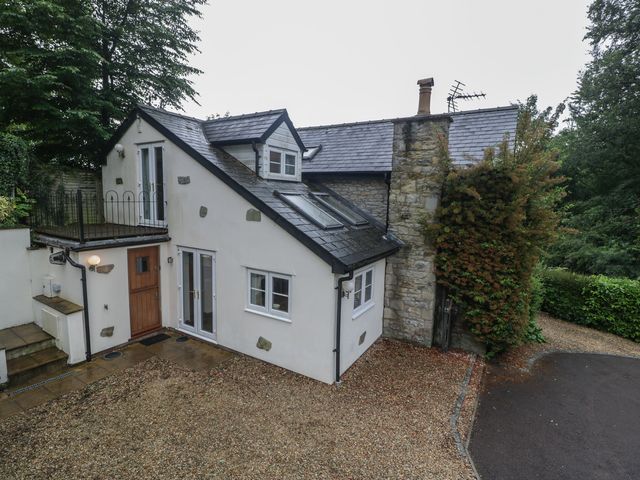 A house with a stone wall and a balcony at Wren Cottage in Ross-on-Wye