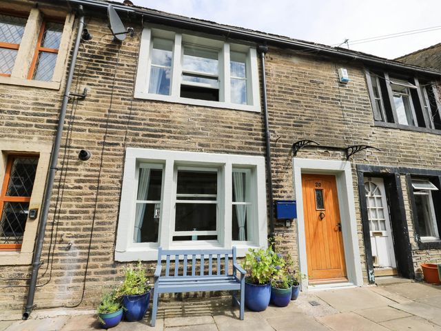 A house exterior with a bench and potted plants at Winberry Cottage in Haworth