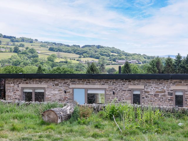A stone building with windows and grass in the foreground at The Stables in Stockport