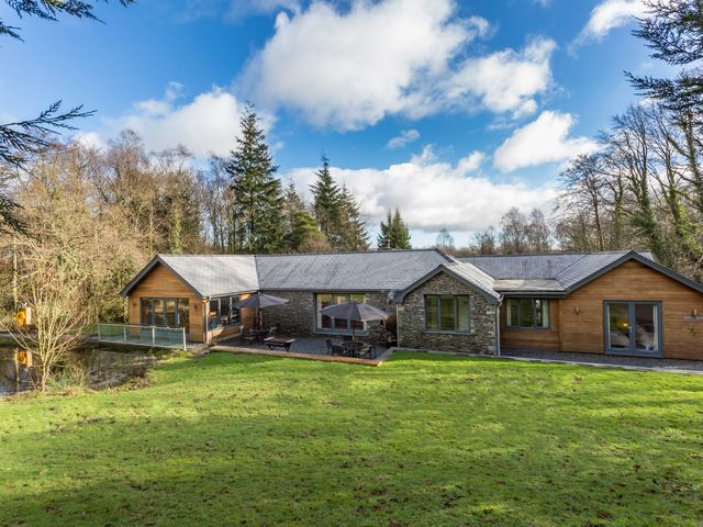 A house with a deck and patio in a grassy area at Bracken Ground in Coniston