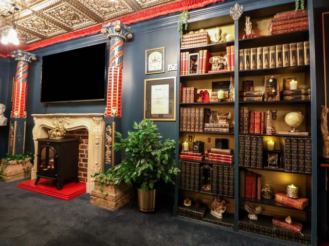A living room with a fireplace and bookshelves at The Hollow in Holywell