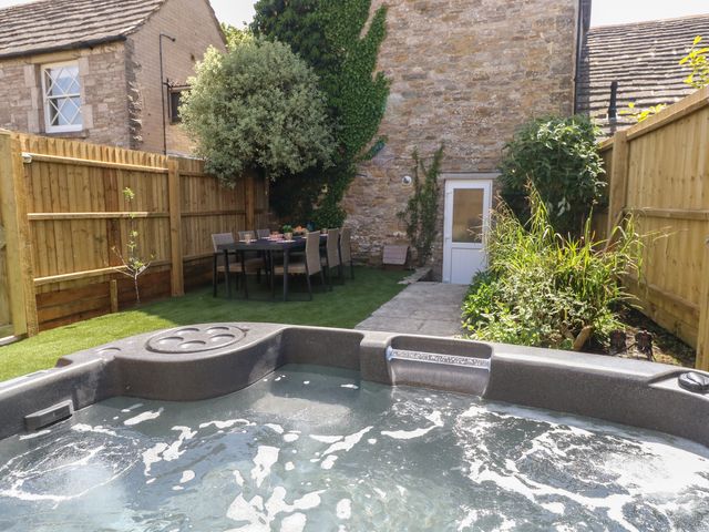 A garden with a hot tub and dining table at Mallow Cottage in Langton Matravers