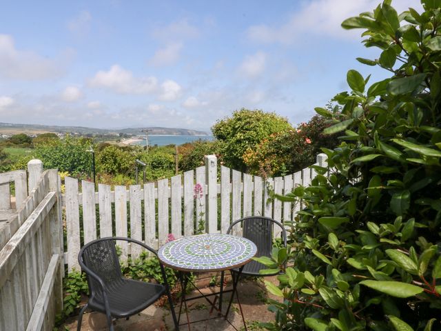 An outdoor seating area with a table and chairs overlooking the sea at Hafan Bach in Abersoch
