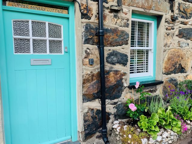 A door and window with a flowerbed at Copper Miners Cottage in Beddgelert, Eryri (snowdonia)