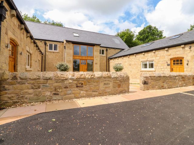 An outdoor view of a stone house with a front door and parking area at Heron View